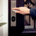 Hand unlocking a smart lock on a front door with a digital access panel