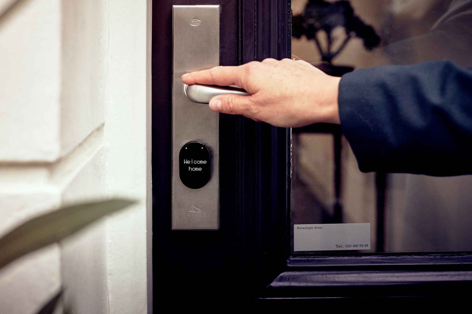 Hand unlocking a smart lock on a front door with a digital access panel