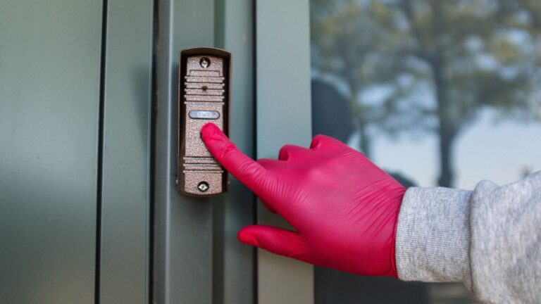 Visitor pressing a modern doorbell on a front door, illustrating the rumored Apple Face ID video doorbell