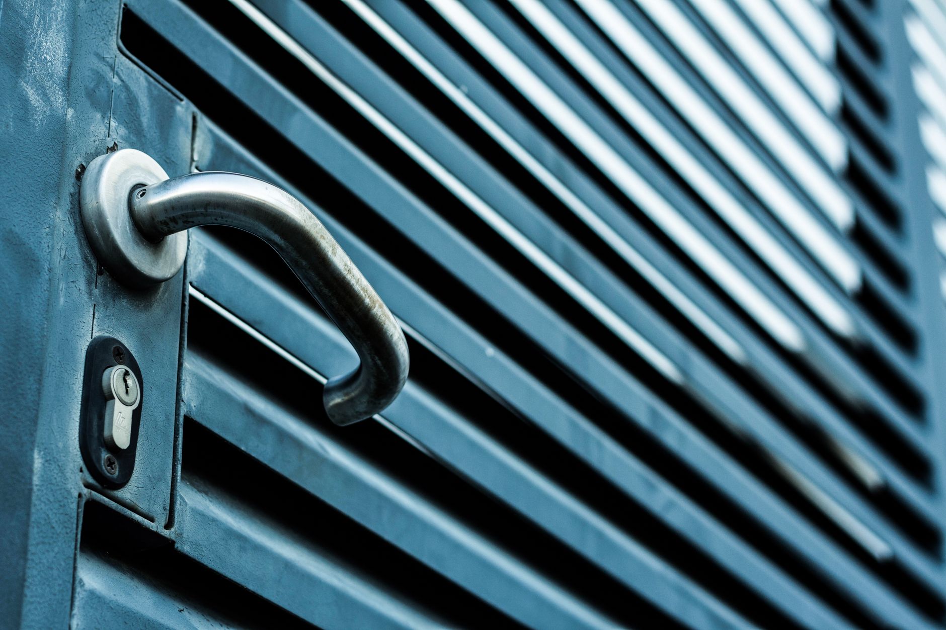 Close-up of a stainless steel door handle and deadbolt lock hardware on a wooden door