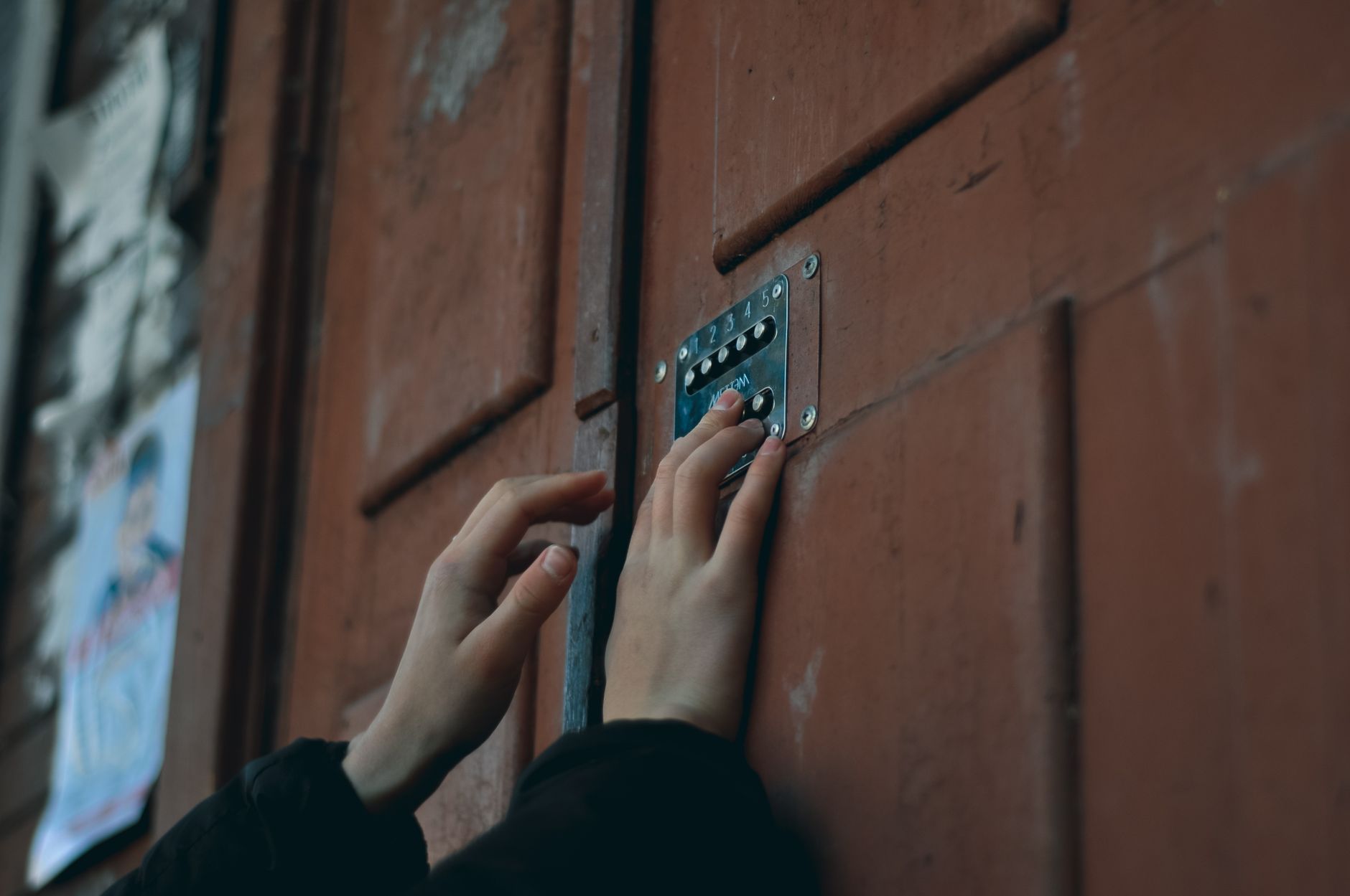 Close-up of hands pressing the backlit keypad on a keyless entry door lock